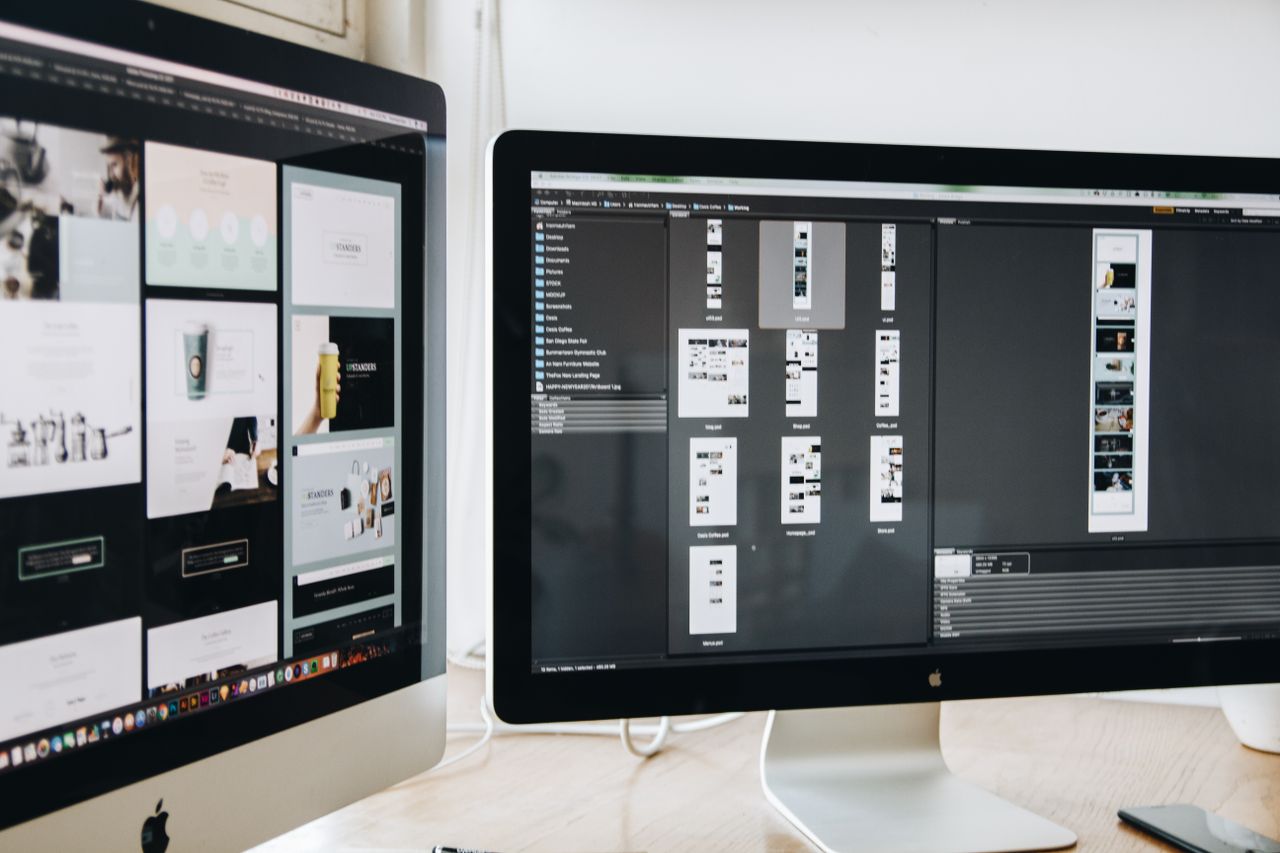 services-04 Savremeni radni prostor sa dva računarska monitora na kojima su prikazani projekti web dizajna, uz naglasak na tehnologiju i produktivnost.